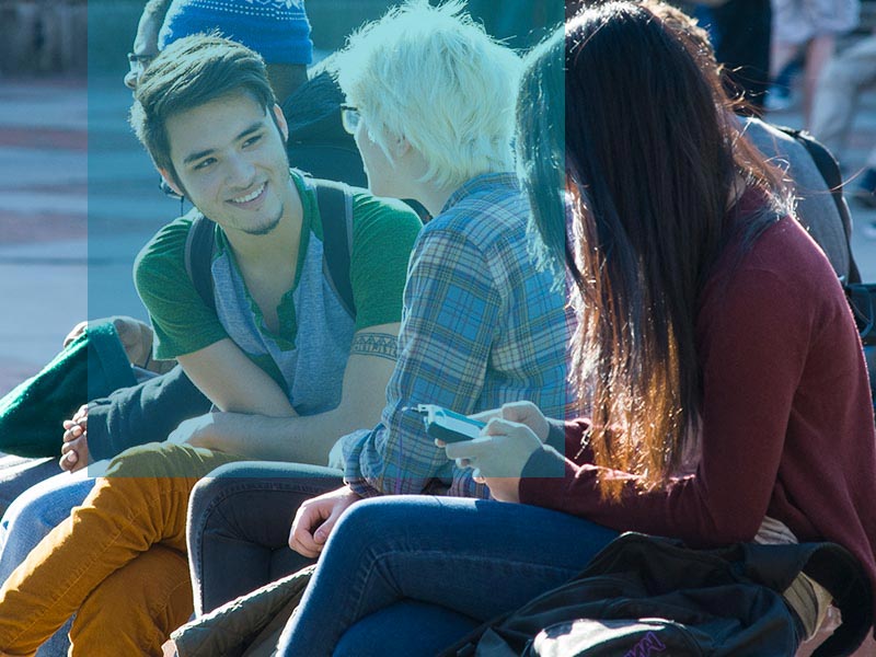 A group of three students chat outside